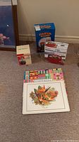 Lot setup showing Pasta Magic blue box, microwave steamer box, instant marinator box, and four colorful placemats arranged on floor