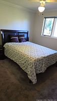 Full view of queen bed with wood and leather headboard, mattress, bed cover, and two pillows.