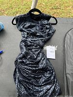 Front view of black sequin sleeveless dress by Alexander Wang on a hanger, showing ruched front detailing.