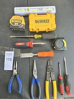 Photo showing the entire lot including DeWalt tape measure, DeWalt case, level, screwdrivers, and pliers spread out on a table.