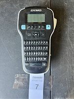 Photo of black Dymo handheld label maker front side showing LCD screen, function buttons, and keyboard.