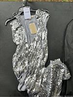 Full view of sleeveless silver sequin dress with zip closure, showing the sequin detail and fabric texture.
