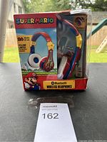 Front view of boxed Super Mario Bluetooth wireless headphones in packaging, showing design and branding.