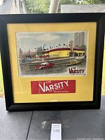 Full view of framed The Varsity artwork with yellow mat and black frame, showing the restaurant illustration and a logo print inside.