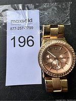 Full view of the gold tone Michael Kors wristwatch showing the front face with crystal bezel.