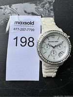 White ceramic Michael Kors watch with a crystal-studded bezel displayed next to a MaxSold tag.