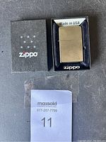 Zippo lighter positioned in original black display box showing 'Made in USA' label and Zippo logo on box.