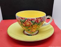 Photo showing tea cup placed on the saucer, highlighting the bright yellow interior and colorful floral exterior.