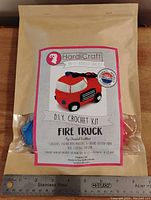 Front view of crochet kit bag showing label and yarn inside with ruler for size reference.