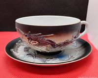 Tea cup and saucer set showing raised moriage dragon design and color gradient