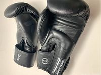Pair of black King Pro boxing gloves displayed side by side on a white surface, showing overall condition and size markings.