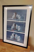 Framed wall print showing three sequential images of a lighthouse with large waves crashing around it.