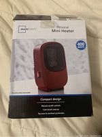 Front of the sealed box showing product name, image, power rating 400 watts, compact design and features including manual control, cool-touch exterior, tip-over and overheat protection.