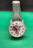 Front view of quartz wristwatch with Santa Claus image on the white dial and green textured band.