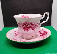 Side view of vintage Royal Albert tea cup positioned on matching saucer showing pink floral design and gold accents.