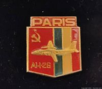 Close-up of Soviet vintage aviation pin with 'PARIS', Soviet hammer and sickle, AH-26 airplane design and tri-color background