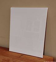 Front view of the unopened stretched white cloth canvas leaning against beige wall.