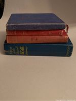 Stack of four vintage hardcover books showing condition and titles visible on spines and covers