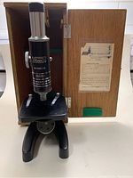 Full view of the vintage Borea microscope inside the open wooden storage box showing front stand, stage, eyepiece tube and wooden box with label