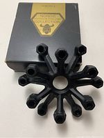 Top view of the black metal vintage Nordic candle holder showing the radial design and the hexagonal candle holders with original box behind.