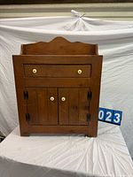 Front view of wooden dry sink cabinet with drawer and doors closed