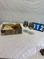 Overall view of pair of wine glasses beside lot number card and packaging box