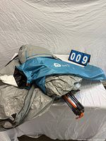 Blue and grey beach tent folded in carry bag with orange poles visible