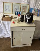 Full lot showing cabinet, air fryer, can opener, framed prints, jars, mug, spatula