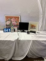 All items arranged on table: two framed prints, monitor, modem box, phone box, smartphone box, DVD player