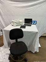 Overall lot view showing HP printer, HP laptop, set-top box on table, and office chair