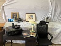 Desk, chair, printer, lamp, heater, pedal exerciser, framed art, books displayed together