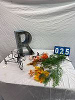 Full lot showing letter R, tricycle stand, flowers