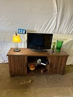 Overall view: TV on stand with lamp and green glass vases