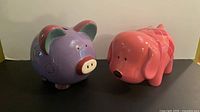 Front view of purple pig and pink dog ceramic banks