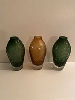 Front view of three coloured etched glass vases