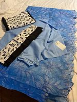 All fabric pieces laid out: blue embroidered lace, light blue cotton, two black-white floral prints