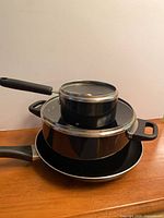 Stacked view of saucepan with lid, pot with lid, and frying pan