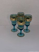 Front view of four turquoise liqueur glasses showing size and set