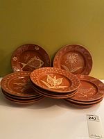 Stack and display of all 12 terra cotta plates showing size and motif variety