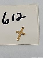 Close-up of front of 14k gold cross charm, showing polished finish and loop for attaching to chain.