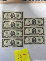 Set of nine $2 bills laid out showing consecutive serial numbers and overall condition.