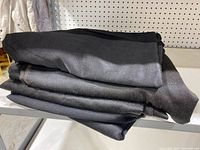 Five folded black table covers stacked on a shelf with clear texture visible.