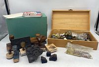 Overall view of wooden box filled with antique door knobs, handles, and multiple stamps including rubber and wooden types, also showing additional stamps and packaging outside box.