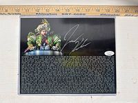 Full view of signed photo in acrylic sleeve with ruler showing dimensions