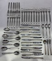 Top view of full flatware set including forks, knives, spoons all organized in Rubbermaid tray.