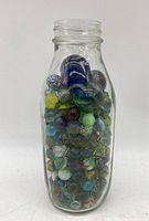 Front view of the clear glass jar full of multicolored marbles, showing the jar and contents.