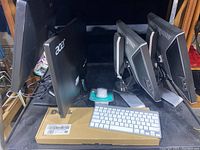 Two keyboards placed on top of a Dell box, Apple Magic Keyboard visible, along with a wireless mouse and four monitors behind them.