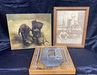 Photo showing all three items together on dark fabric with painting on left, framed photo on right, and wooden utensil art in front center