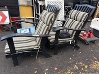 Pair of black metal outdoor rocker chairs with striped cushions attached by ties.