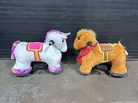 Side view of white unicorn and brown horse plush ride-on toys, showing overall size, plush design, handlebars, and wheels.